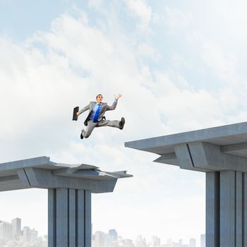 Businessman jumping over a gap in the bridge as a symbol of bridge