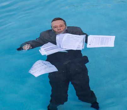 Senior caucasian businessman in suit sinking underwater in deep blue pool worried about being underwater with mortgage payments