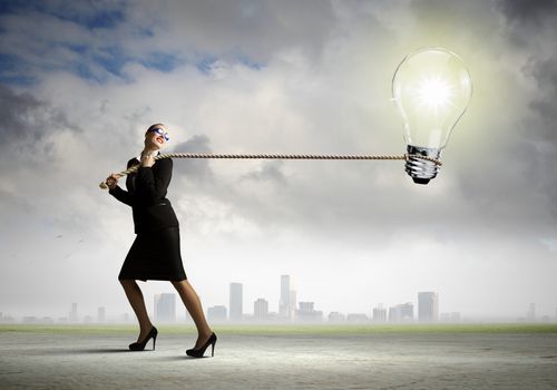 Image of businesswoman pulling electrical bulb with rope