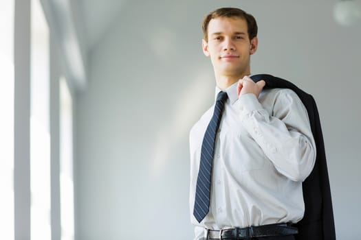 Handsome smiling businessman holding jacket on his shoulder