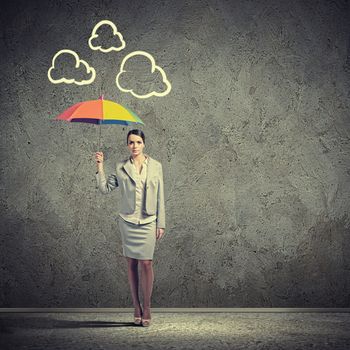 Young business woman in suit standing and holding an umbrella