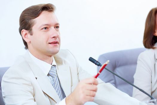 Image of young businessman sitting at table at business meeting