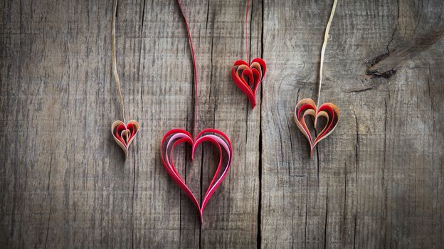 Hanging paper heart decoration on wood background. 