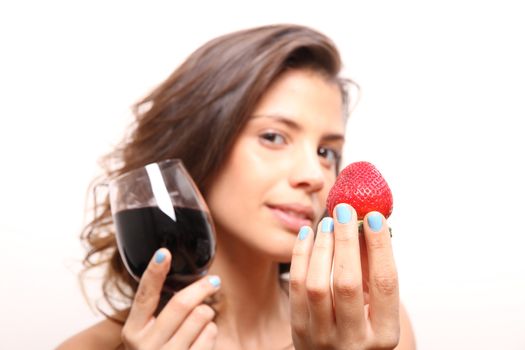 Portrait of a beautiful, latin Woman eating a Strawberry and drinking wine.