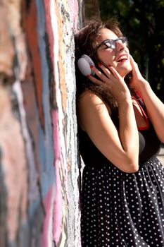 A vintage dressed girl listing to music in a urban environment.