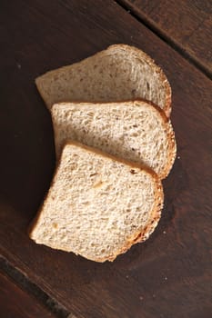 Close up of three slices of bread. Natural wood background.