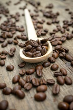 A Wooden Spoon with coffee beans on wood textured background