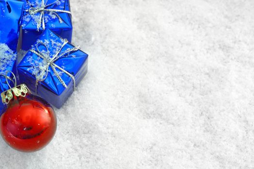 Blue Christmas gifts in the snow + red ball