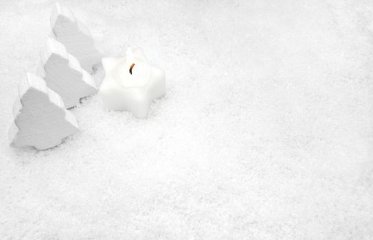 White candle and fir trees in the snow