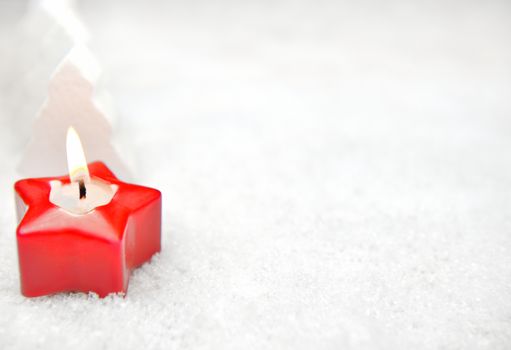 Red candle and fir trees in the snow