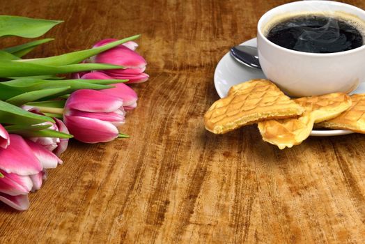 Fresh tulips, a cup of hot, steaming coffee and freshly baked waffles