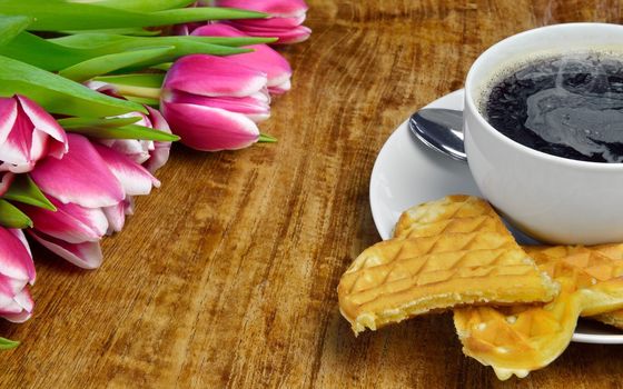 Fresh tulips, a cup of hot, steaming coffee and freshly baked waffles