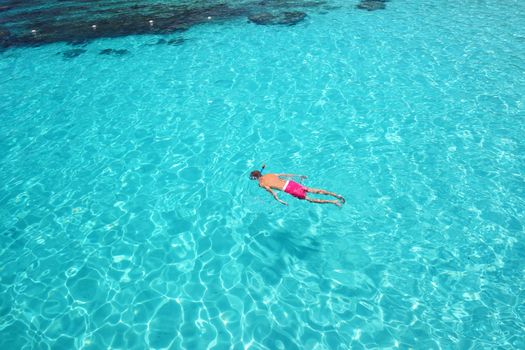 Man snorkeling in crystal clear turquoise water at tropical beach