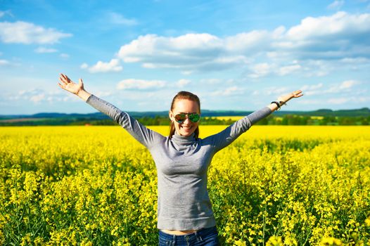 Girl with outstretched arms at colza field