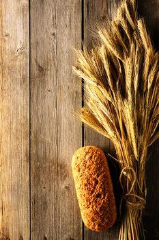 Rye spikelets and bread on wooden background