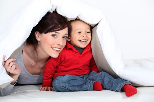 Woman and child hiding under a duvet