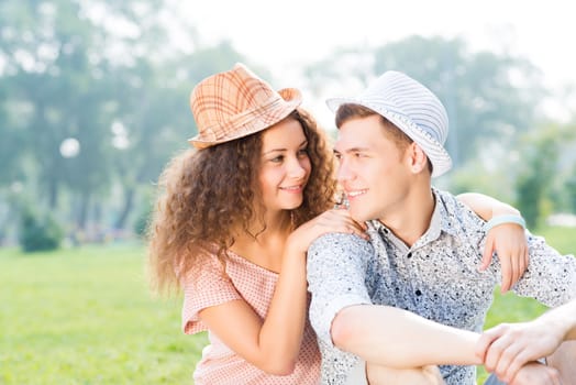 romantic couple lying on the grass in the summer park, spending time with loved ones