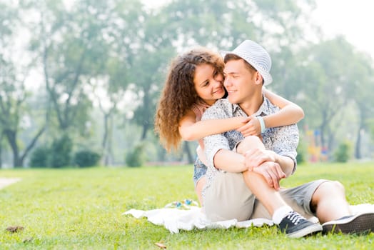 romantic couple lying on the grass in the summer park, spending time with loved ones