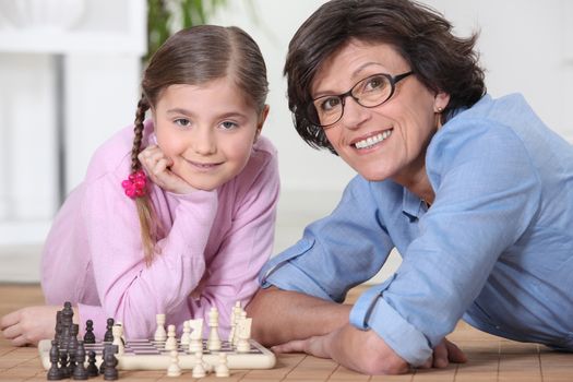 Woman playing chess with little girl