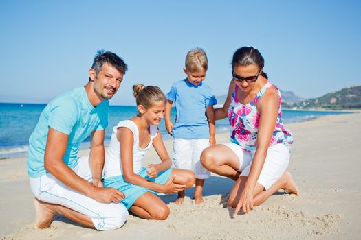 Family of four having fun on tropical beach