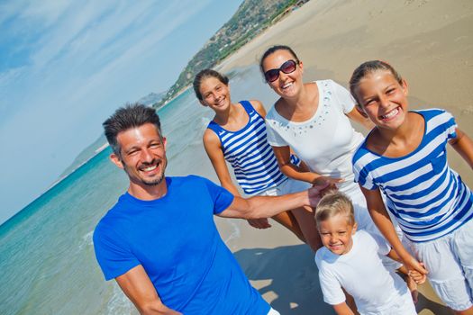 Photo of happy family with three kids running down the beach