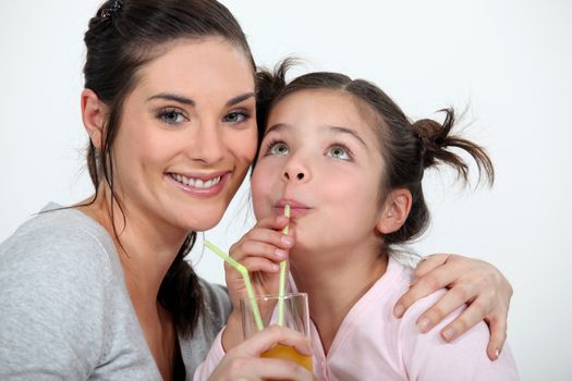Mother and daughter drinking through straws