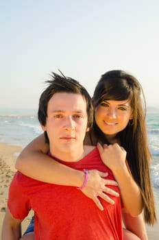 Girl riding piggyback on the beach with her boyfriend