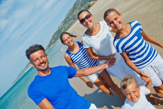 Photo of happy family with three kids running down the beach