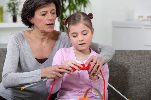 grandmother teaching granddaughter how to knit