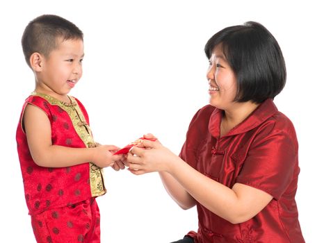 Asian Chinese boy receiving red paper packet or monetary from parent on Chinese New Year festival, with traditional Cheongsam isolated on white background.