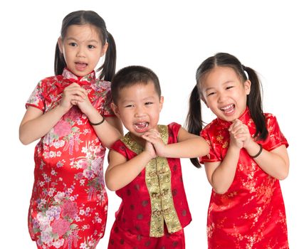 Little oriental children wishing you a happy Chinese New Year, with traditional Cheongsam standing isolated on white background.