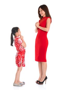 Happy Chinese New Year! Full length Chinese parent and child in traditional Chinese cheongsam greeting to each other, isolated on white background