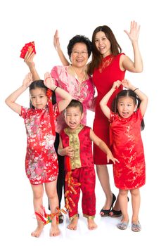 Group of happy  smiling multi generations Asian Chinese family wishing you a happy Chinese New Year, with traditional Cheongsam standing isolated on white background.