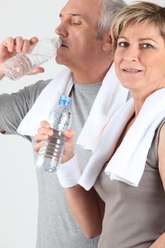senior couple drinking water after training