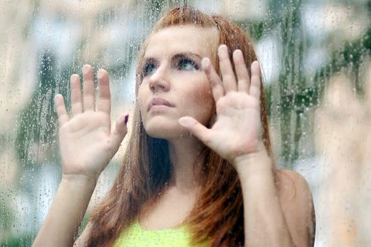 Portrait of a young woman near the window after the rain