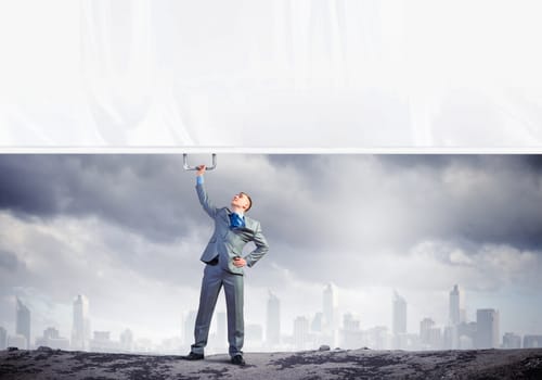 Image of young businessman pulling blank banner from above