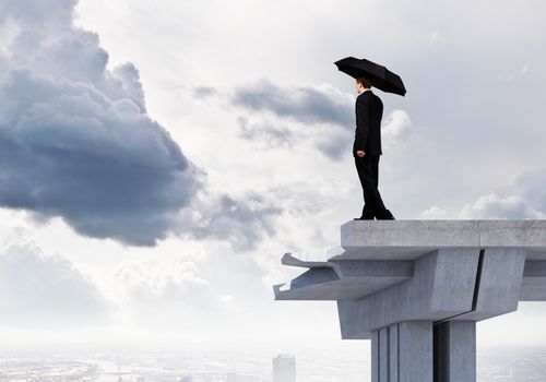 Image of businessman with umbrella standing at the edge of bridge