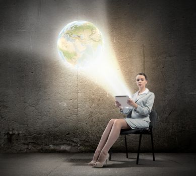 Image of businesswoman sitting on chair with tablet pc in hands