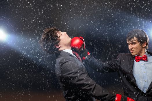 Two young businessman boxing againts dark background . conceptual collage