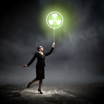 Image of businesswoman in goggles holding balloon with radioactivity symbol