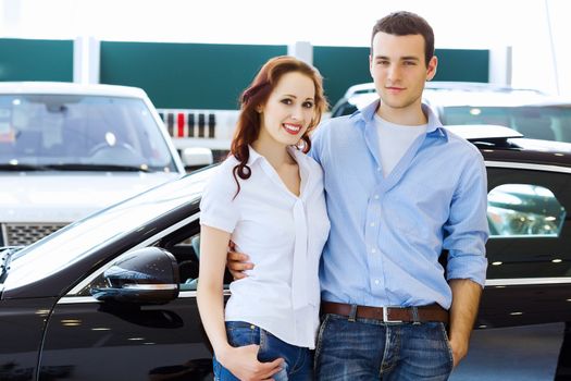 Two pretty young people smiling standing near car