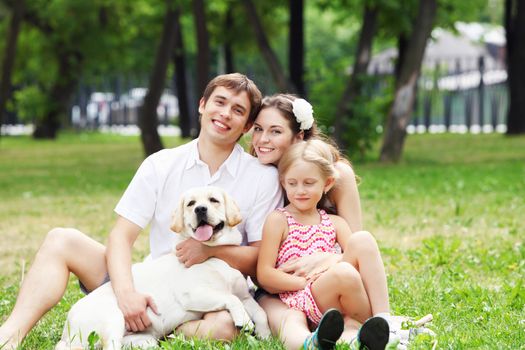 Young Family Outdoors in summer park with a dog