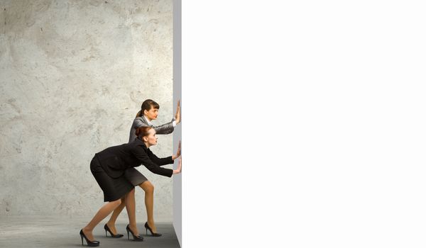 Two businesswoman pushing blank white banner. Place for text