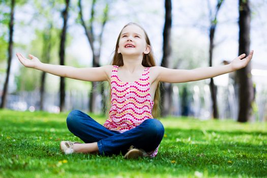 Image of little cute girl sitting on grass in park