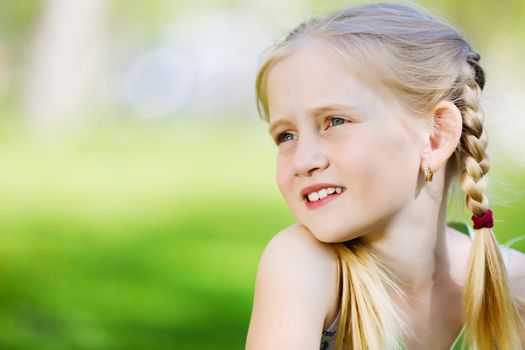 Image of little cute girl sitting on grass in park