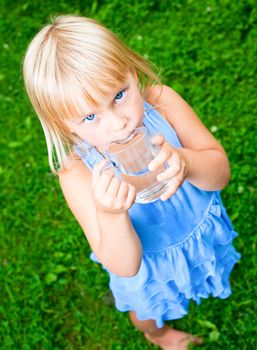 Cute little girl drinking water outdoors