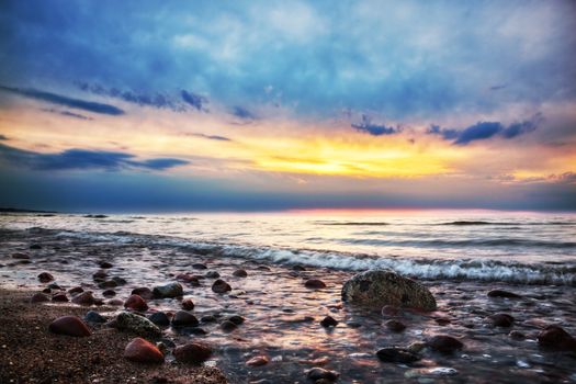 Dramatic colorful sunrise on a rocky beach. Baltic sea