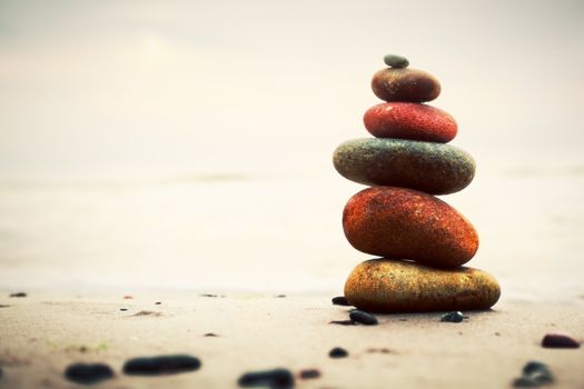 Stones pyramid on sand symbolizing zen, harmony, balance. Ocean in the background