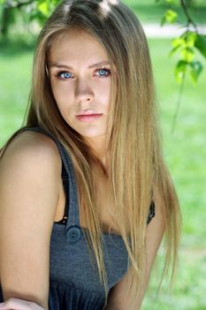 Portrait of the young beautiful woman on a background of leaves of a birch