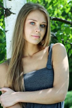 Portrait of the young beautiful woman on a background of leaves of a birch